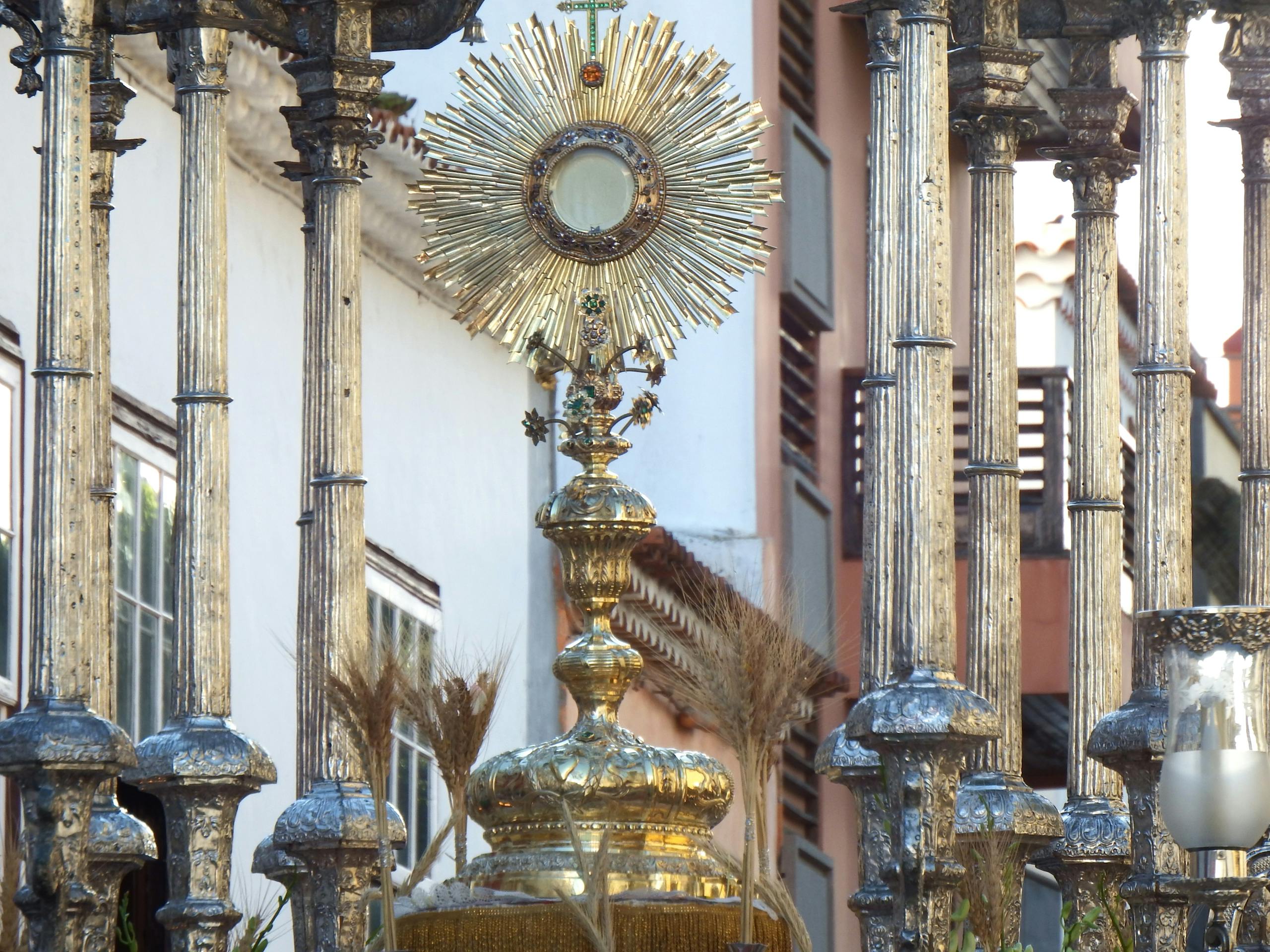 Detailed image of a gold monstrance used in an outdoor religious procession.